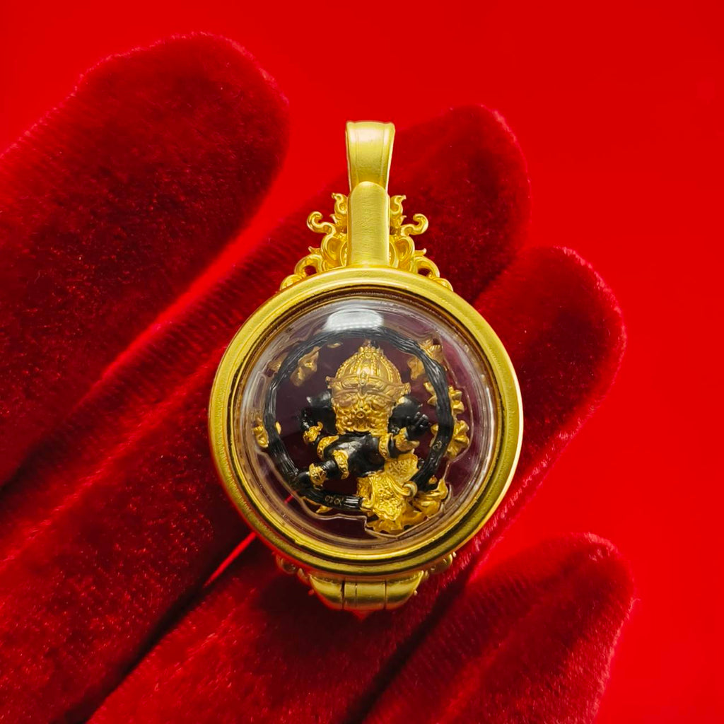 Gold Phra Brahma amulet for protection displayed against a red background with a hand for scale