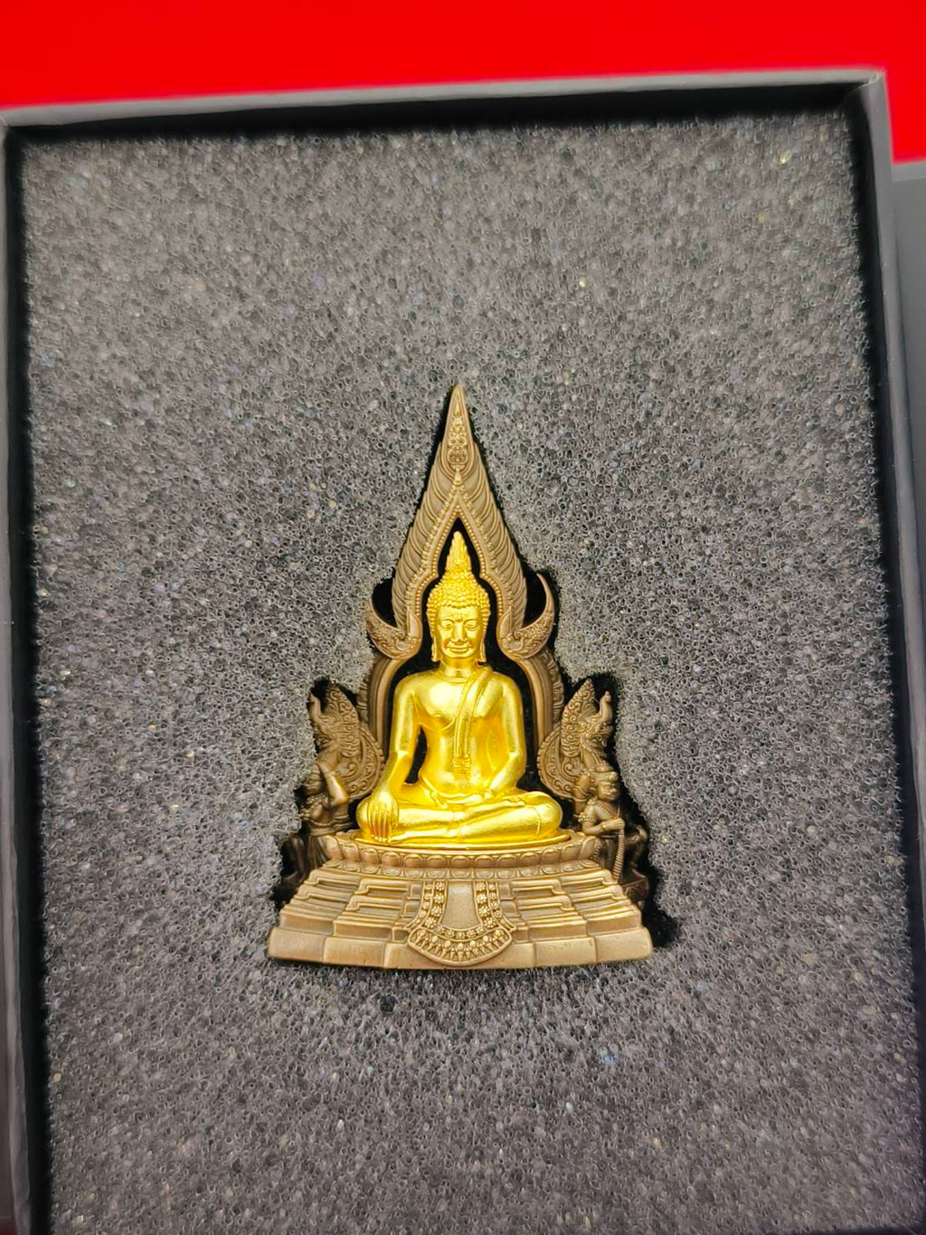 Phra Buddha Chinnarat amulet in gold and bronze color, beautifully detailed and framed in elegant packaging