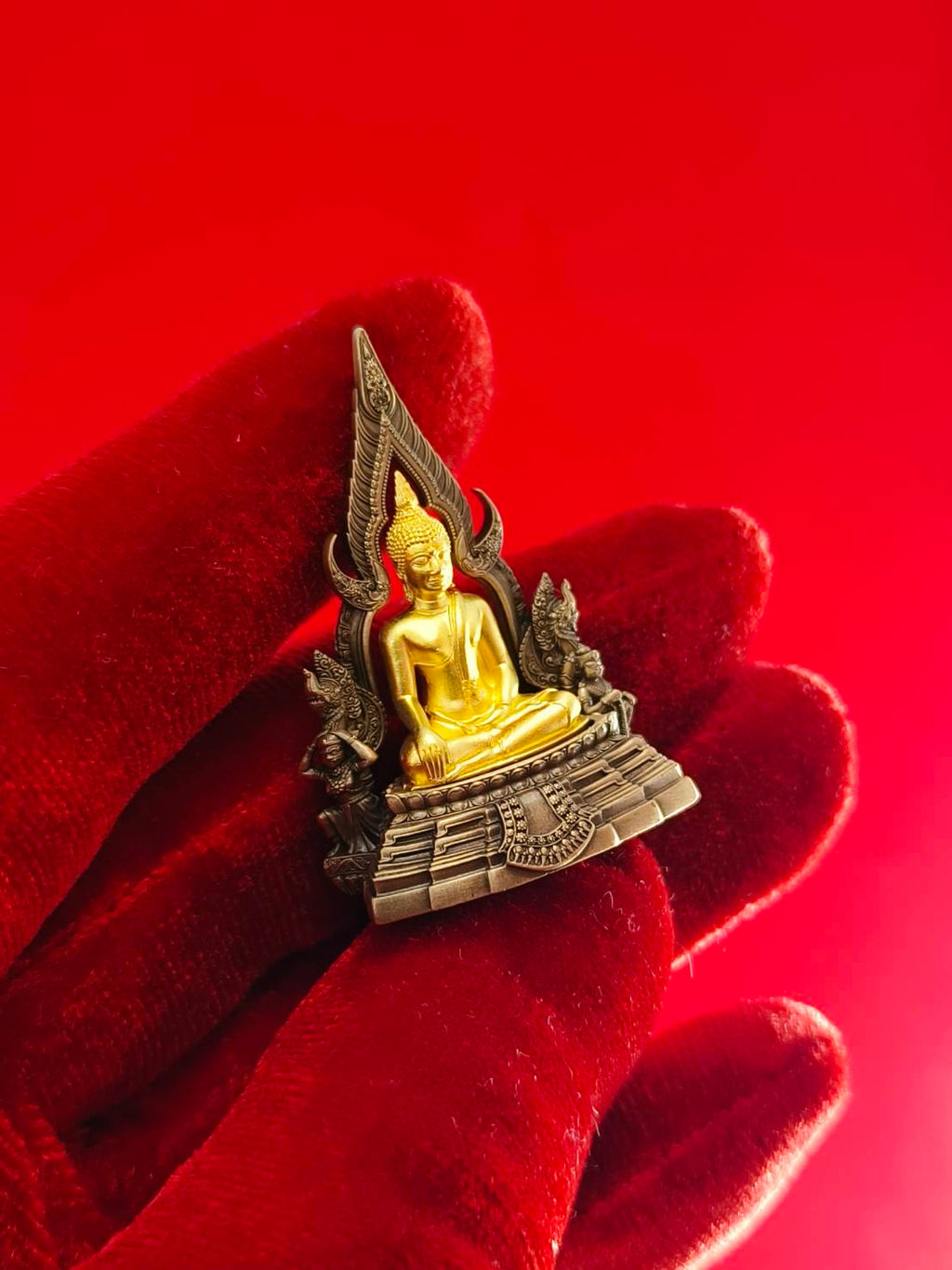 Phra Buddha Chinnarat amulet with intricate details on a red background, ideal for home decor and spiritual ambiance