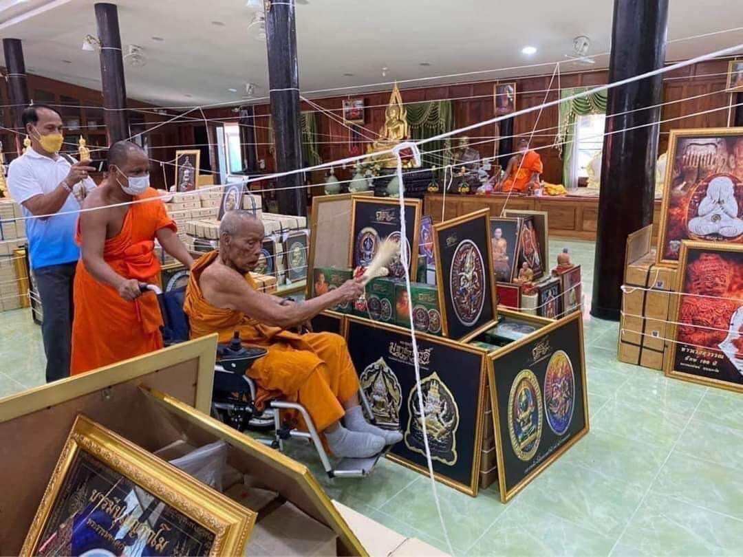 Buddhist monk blessing Phra Buddha Chinnarat amulet collection in a temple setting
