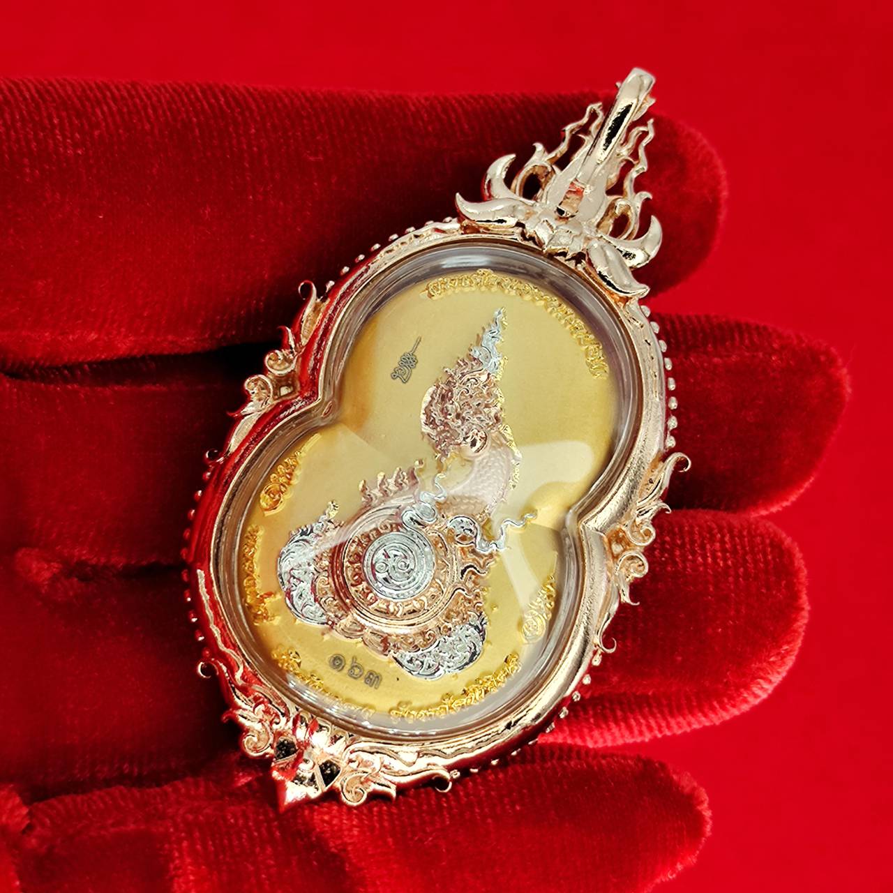 Phra Naga Prok amulet for protection displayed in ornate gold casing on a red background