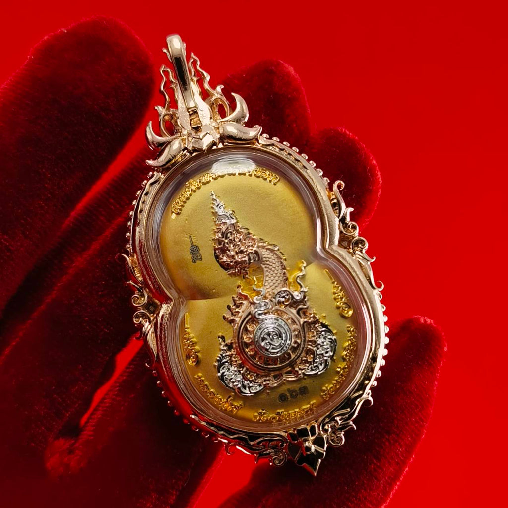 Phra Naga Prok amulet for protection in ornate gold casing, held against a red background
