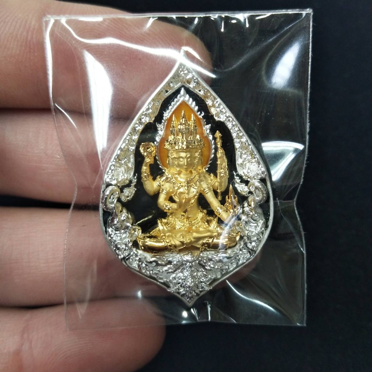 Phra Phrom elephant guardian amulet in a protective casing, showcasing intricate gold details.