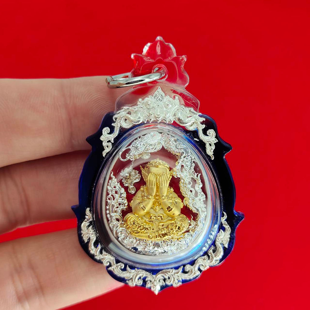 Phra Pidta amulet for wealth encased in a decorative clear pendant with intricate details