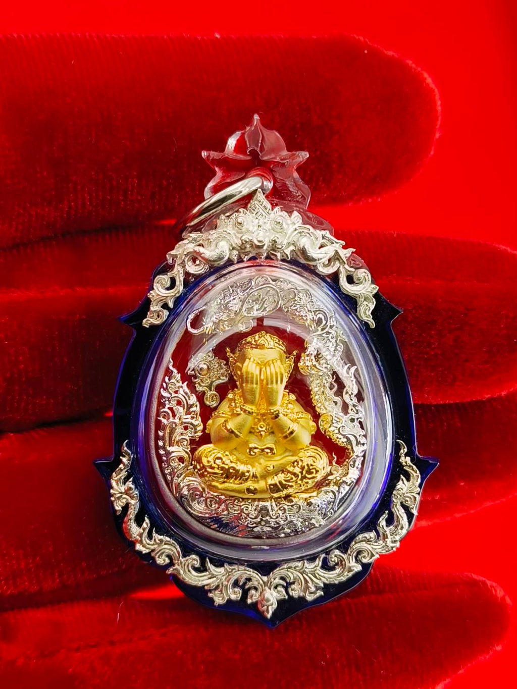 Phra Pidta amulet for wealth with intricate design and golden statue in a protective casing
