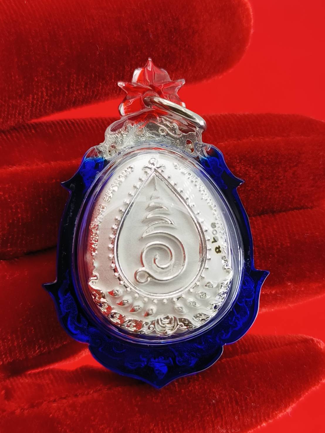 Phra Pidta amulet for wealth with detailed silver design and blue frame, perfect for collectors and home decor