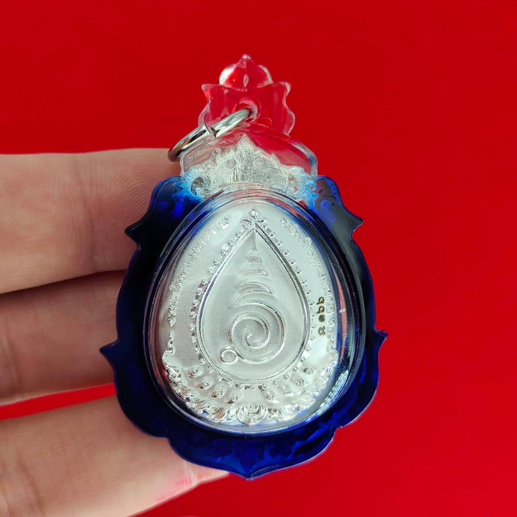 Phra Pidta amulet for wealth in a decorative blue and clear casing, perfect for collectors