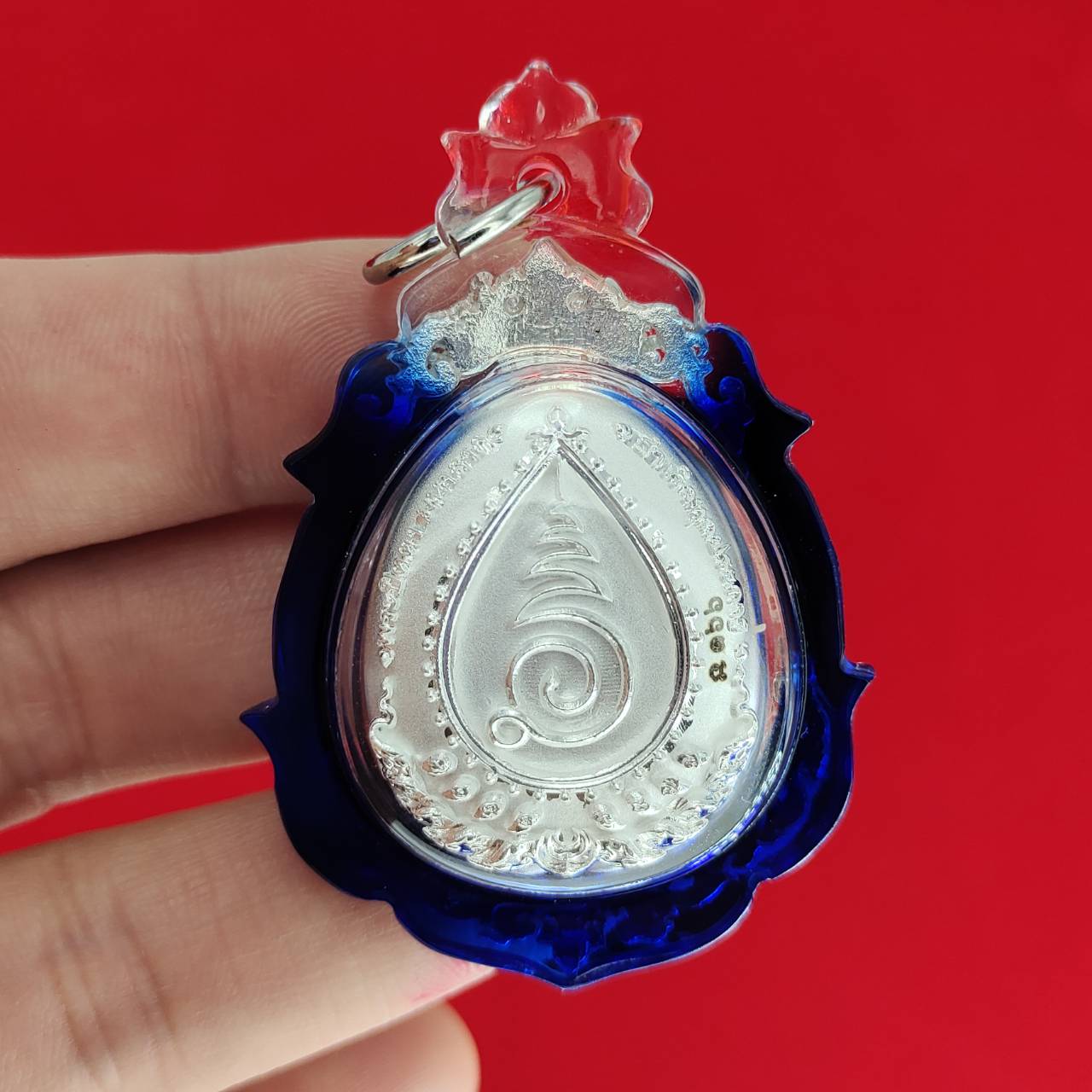 Phra Pidta amulet for wealth with intricate design in a blue protective casing