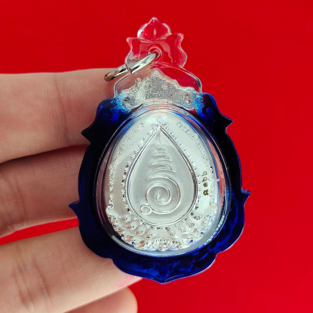 Phra Pidta amulet for wealth featuring a silver design encased in a blue protective frame