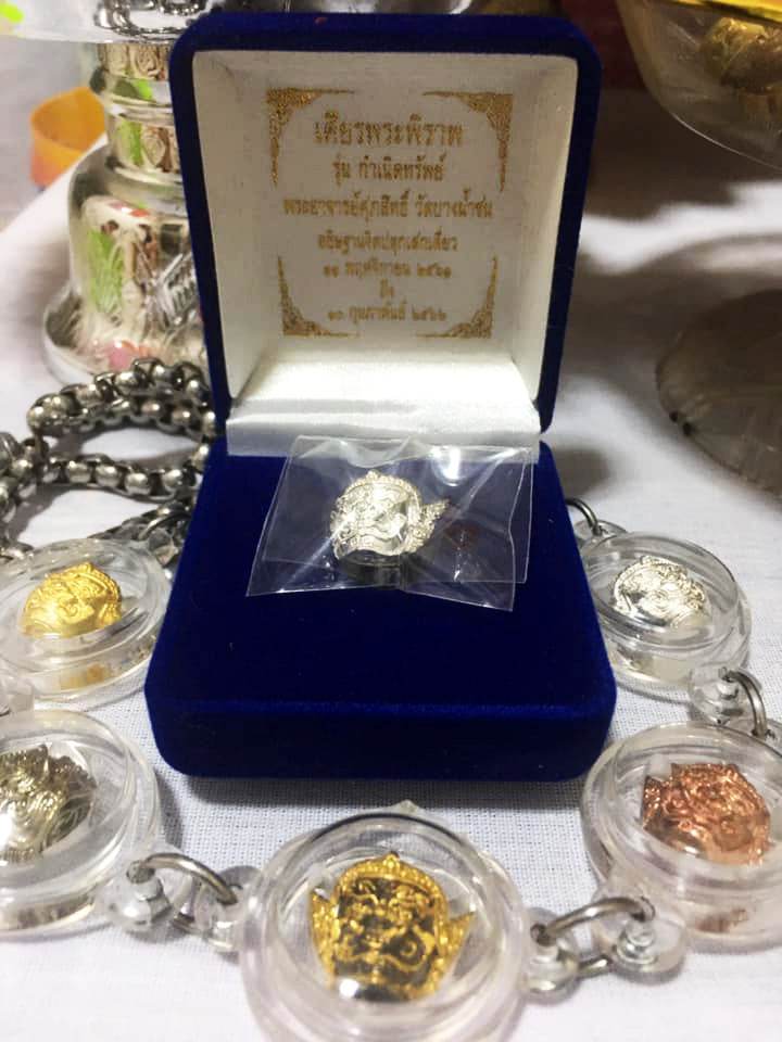 Phra Pirap amulet for power displayed in a blue velvet box with gold and silver medallions around it