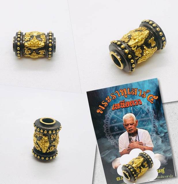 Phra Rahu amulet for luck featuring intricate gold and black design with accompanying pamphlet