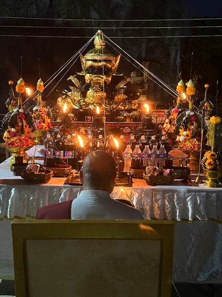 Phra Rahu amulet for luck displayed at a serene altar surrounded by candles and floral offerings