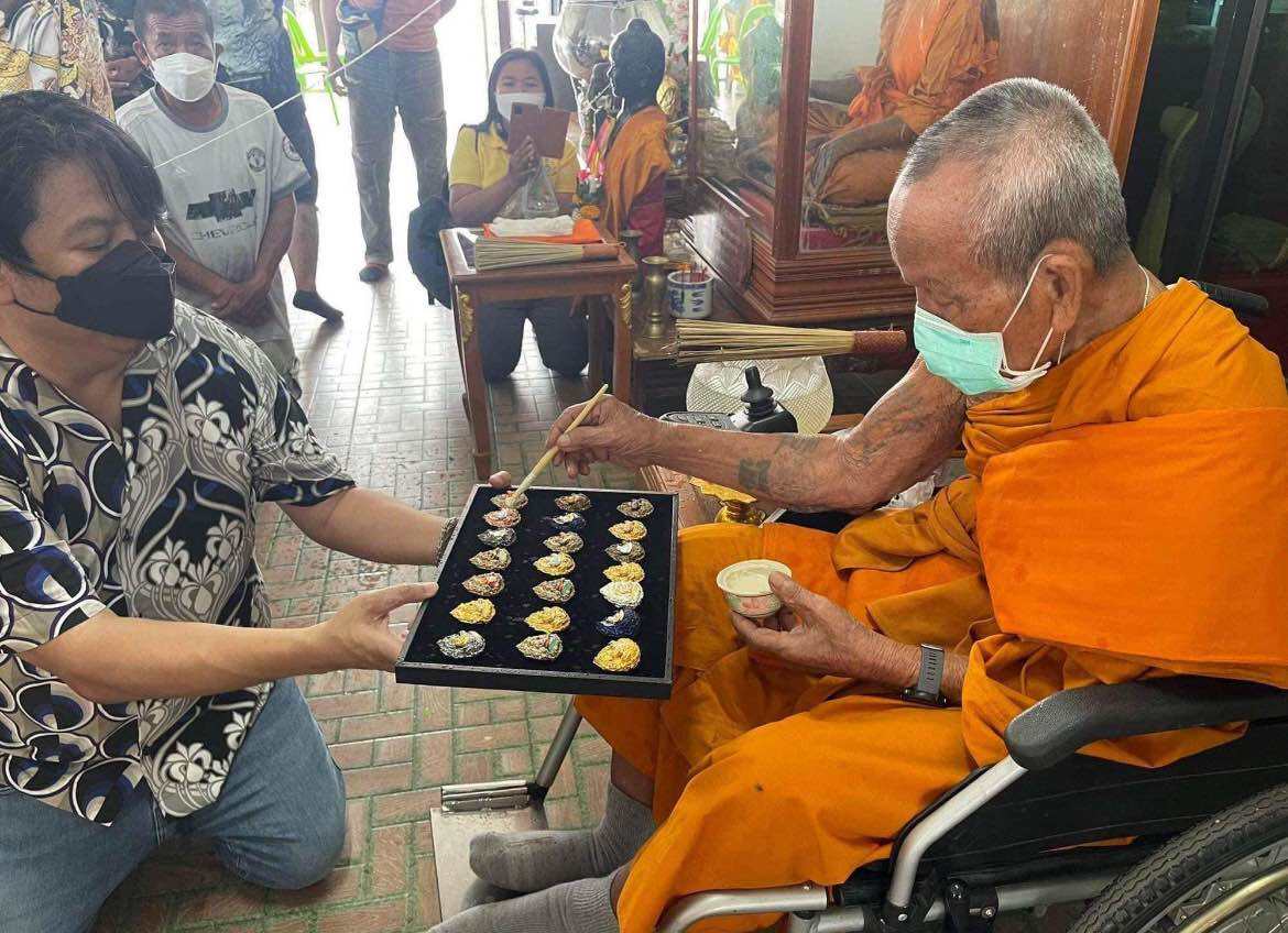 Phra Sangkajai and Phra Upakut amulet display during a traditional blessing ceremony by a monk