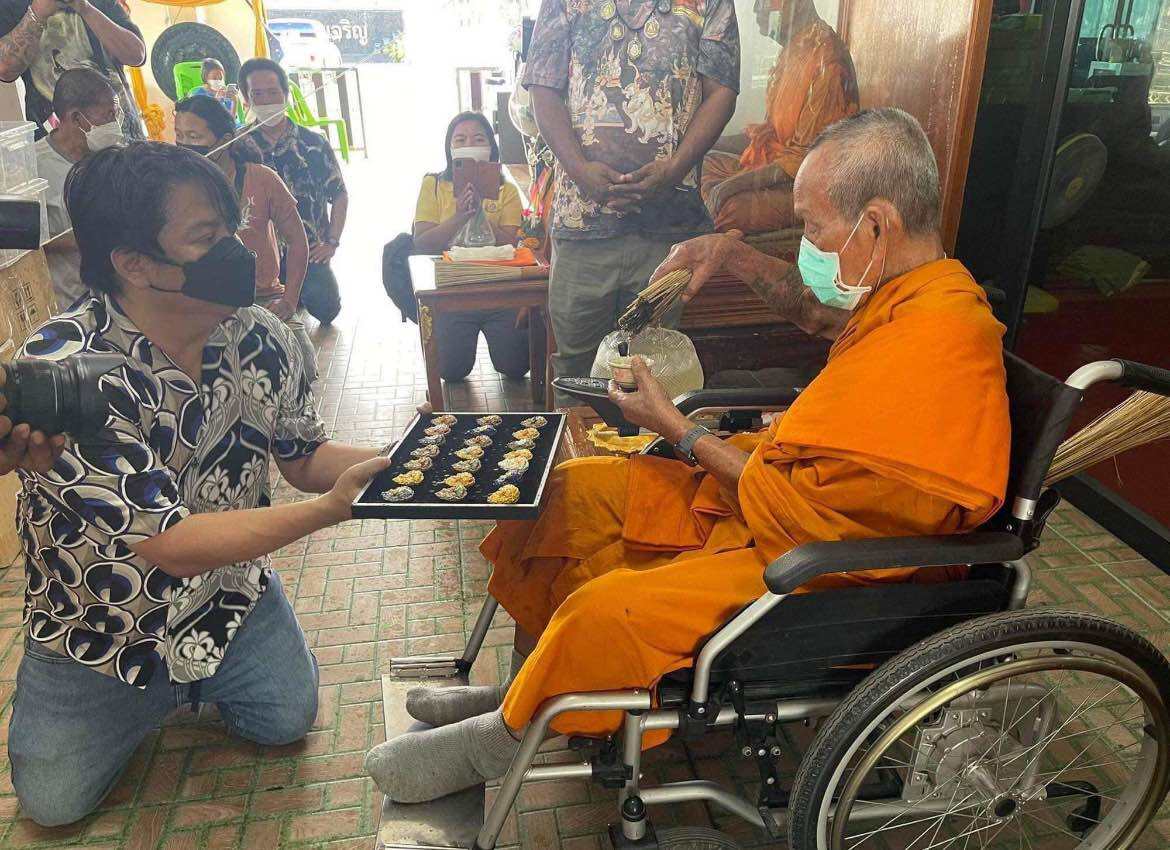 Phra Sangkajai and Phra Upakut amulet blessing ceremony with a monk in an orange robe