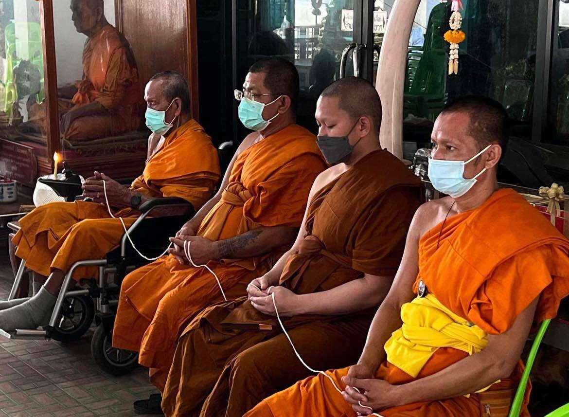 Monks in orange robes performing rituals for Phra Sangkajai and Phra Upakut amulet at a Thai temple