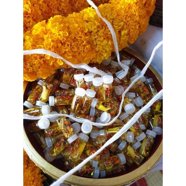 Assorted powerful communication amulet Thailand in small bottles displayed on a decorative tray with marigold flowers