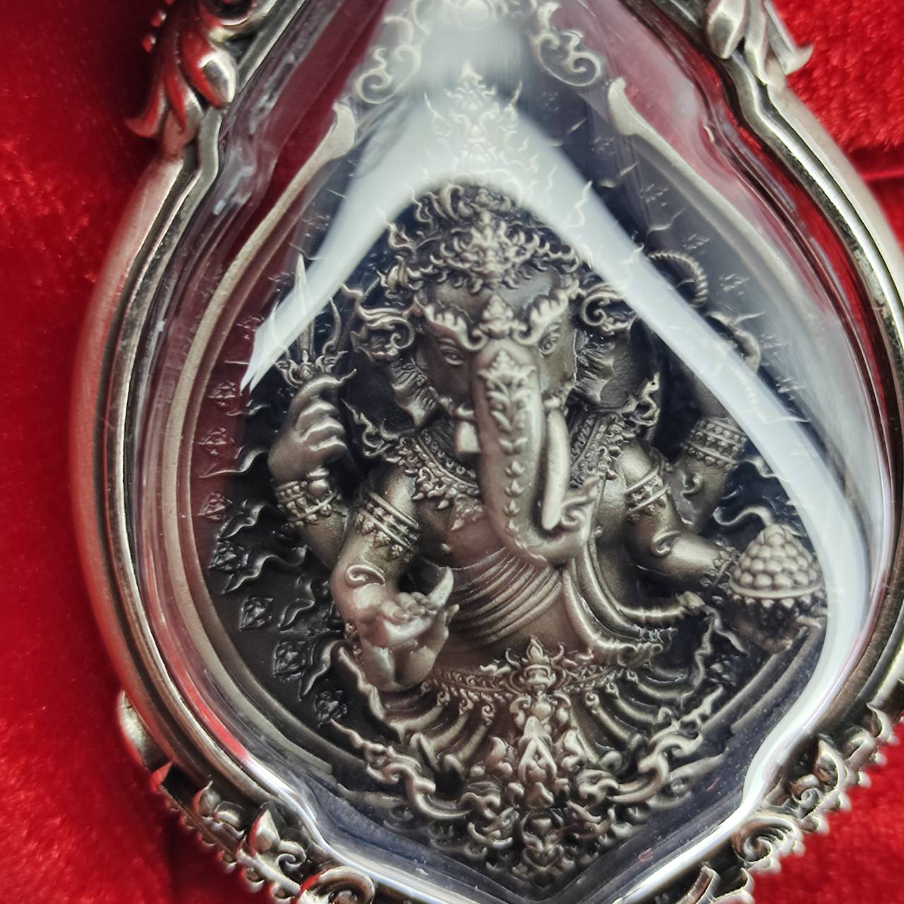 Intricate prosperity Ganesh pendant Thailand in a decorative frame on a red background
