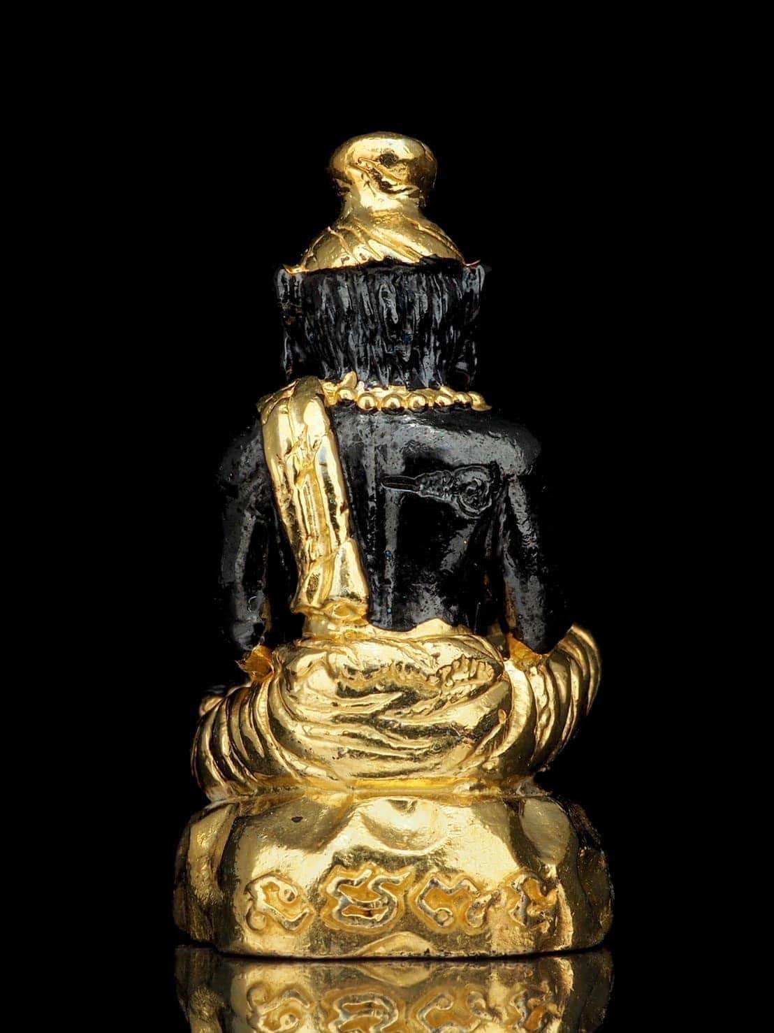 Rear view of Pu Jao Saming Prai spirit talisman in black and gold with intricate detailing against black background