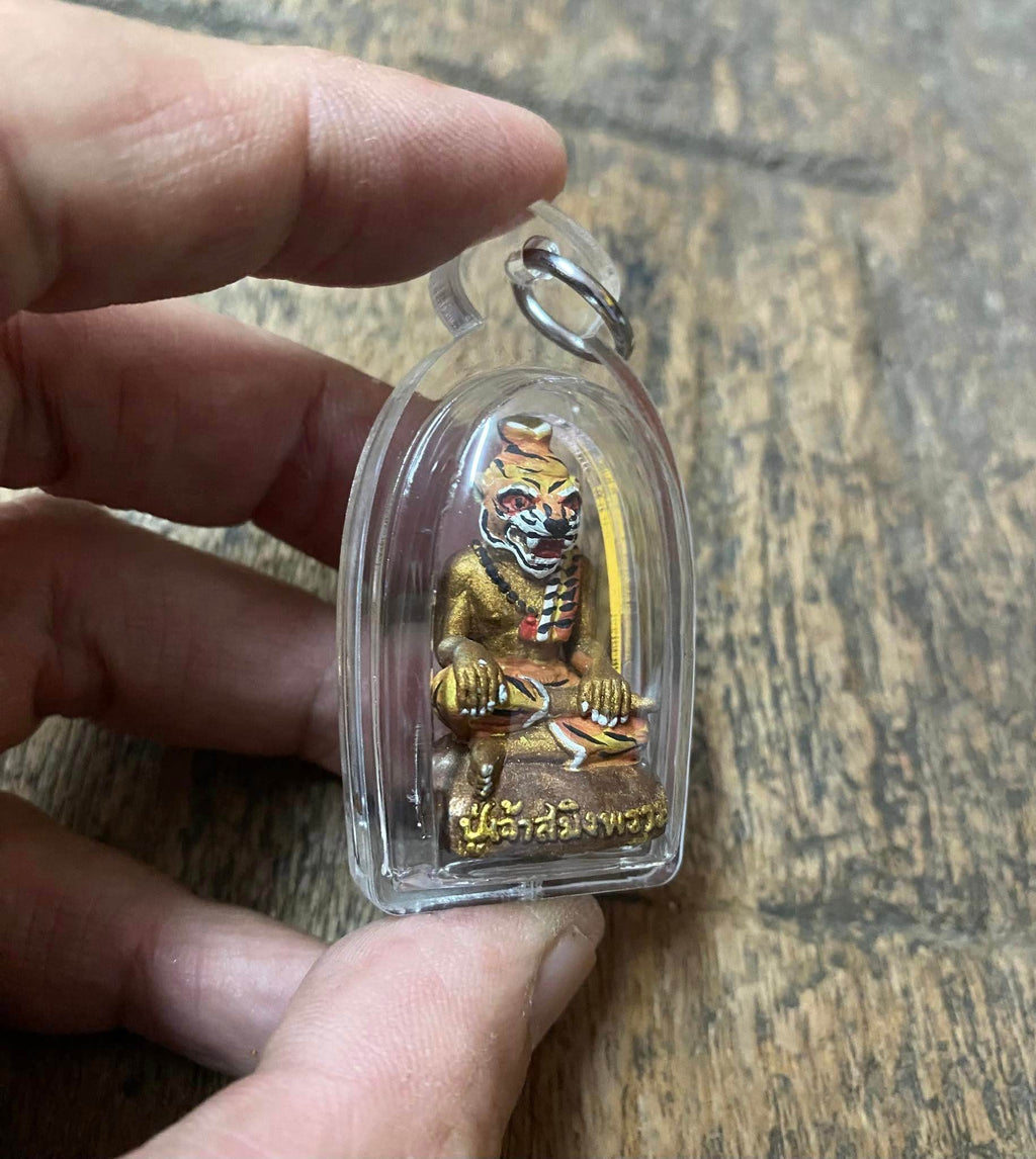 Hand holding Pu Jao Saming Prai spirit talisman encased in clear plastic from Thai Blessing Co