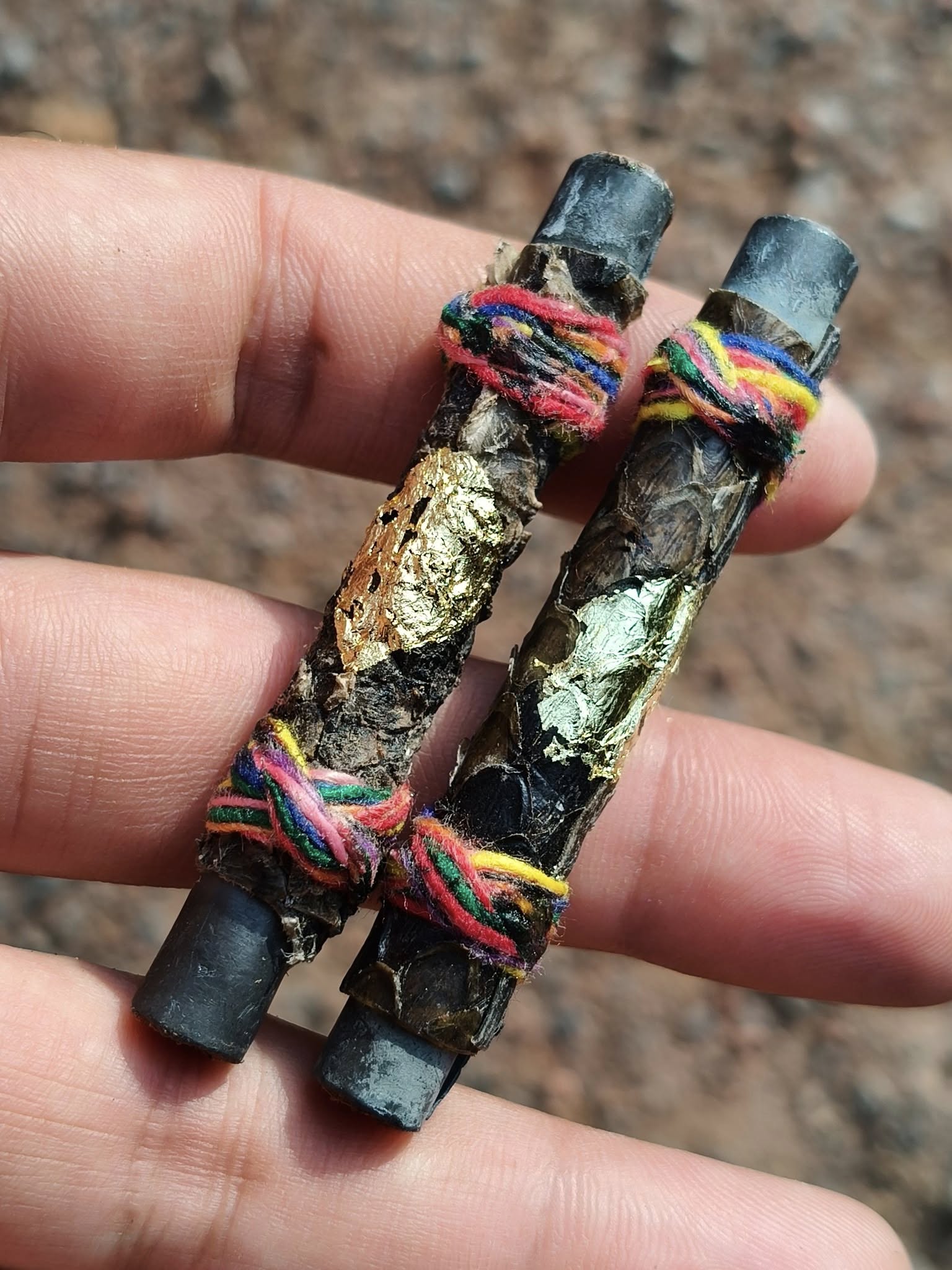 authentic Thai python skin talisman pair with gold leaf and colorful thread wraps held in hand