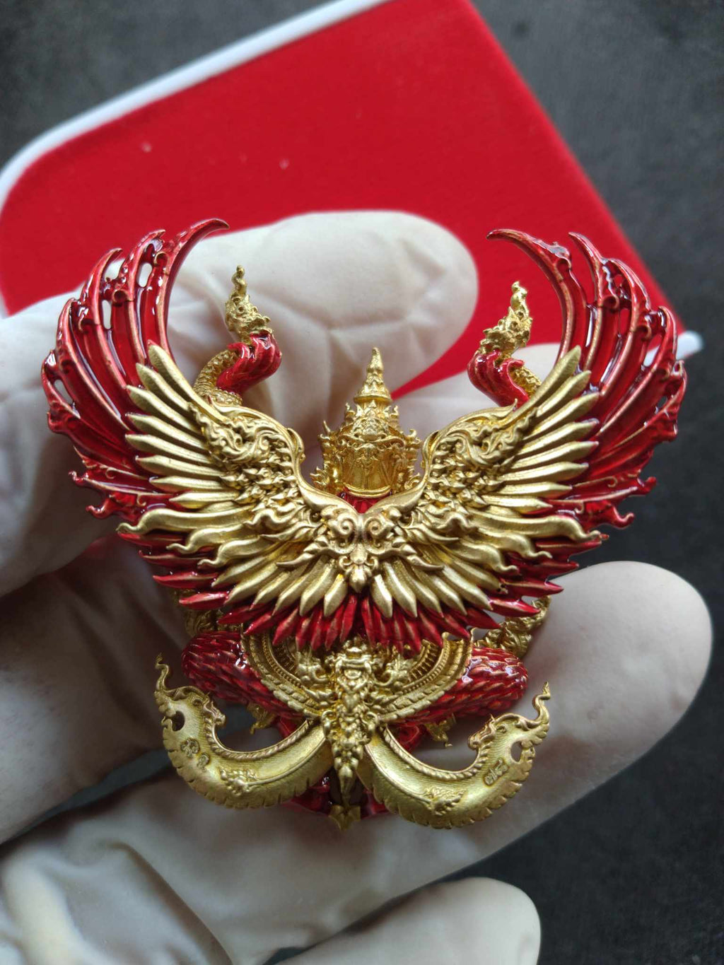 Phaya Krut Maha Amnat Amnat 4-Claws – Ruay Ruay Ruay Edition gold and red Garuda pendant held in gloved hand