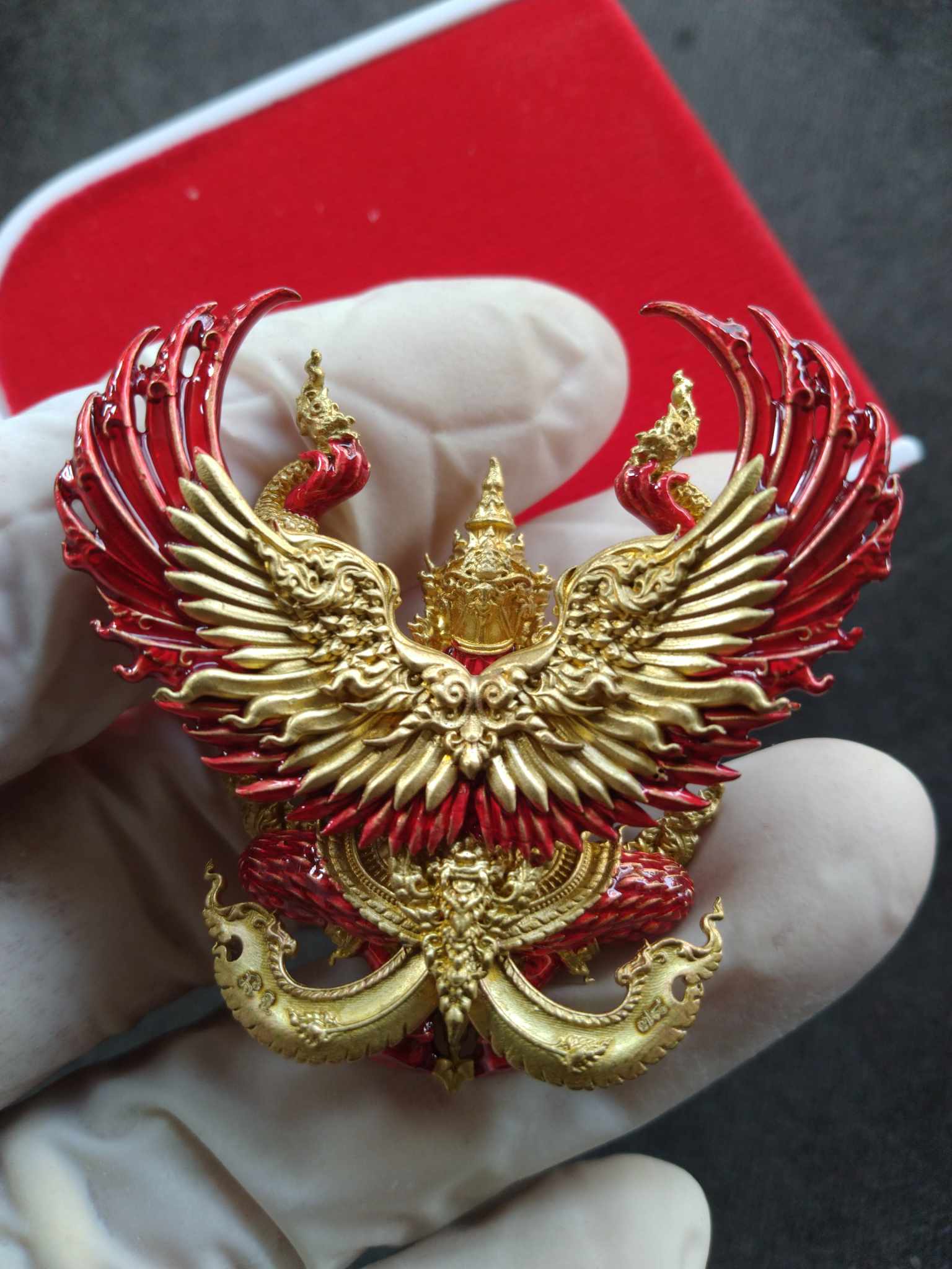 Ornate gold and red Phaya Krut pendant held in gloved hand Phaya Krut Maha Amnat Amnat 4-Claws – Ruay Ruay Ruay Edition