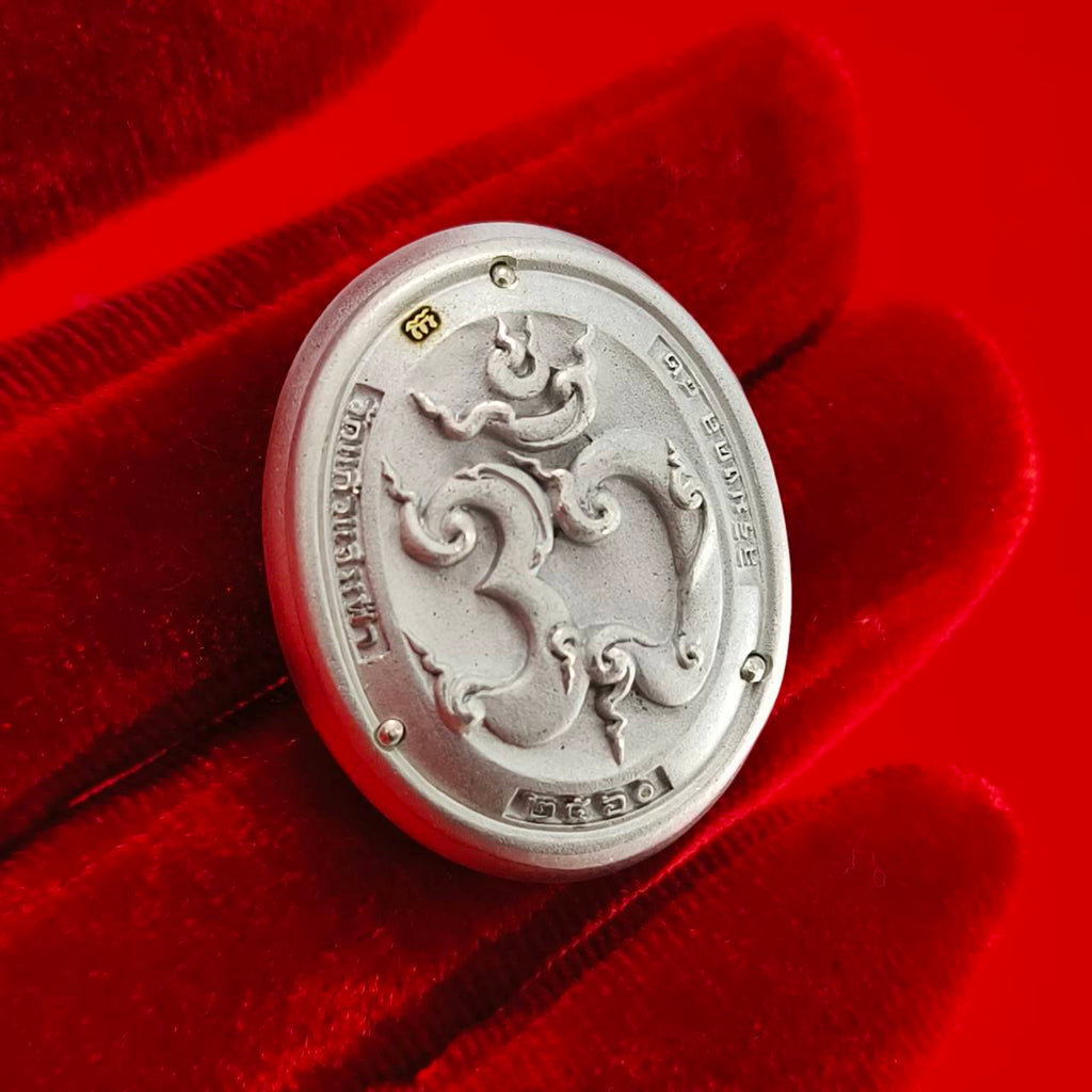 Sacred Ganesha talisman for fortune in a silver finish displayed on a red velvet background.