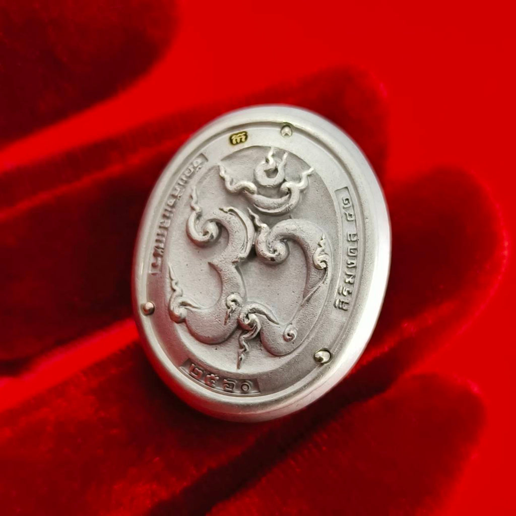 Sacred Ganesha talisman for fortune, engraved with intricate designs on a silver background.