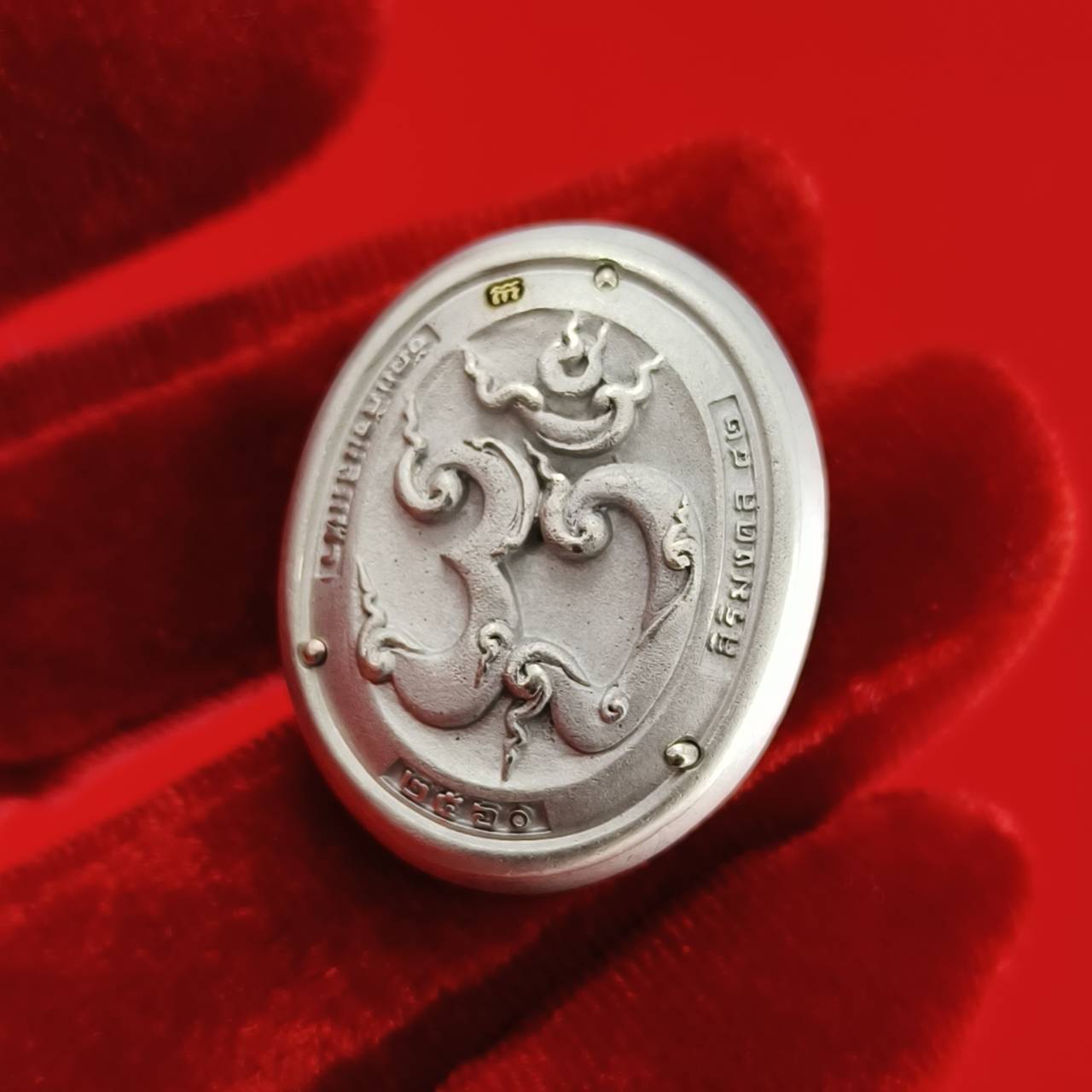 Sacred Ganesha talisman for fortune, engraved with intricate designs on a silver background.
