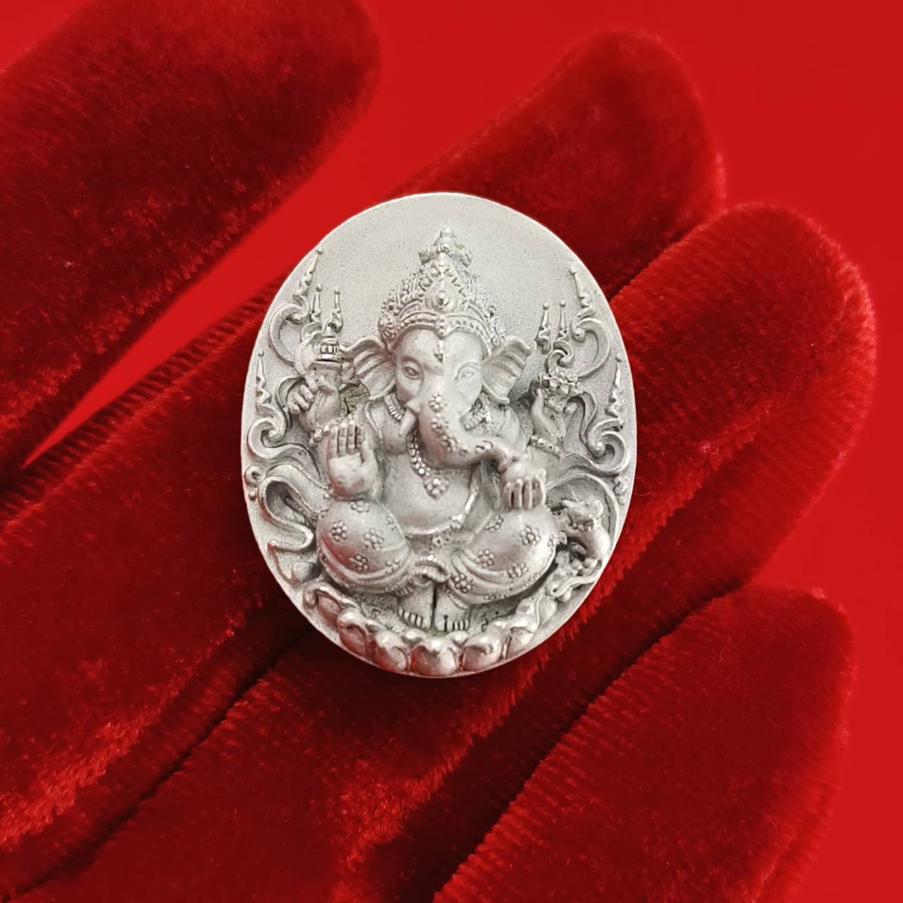 Sacred Ganesha talisman for fortune intricately designed in silver on a red background
