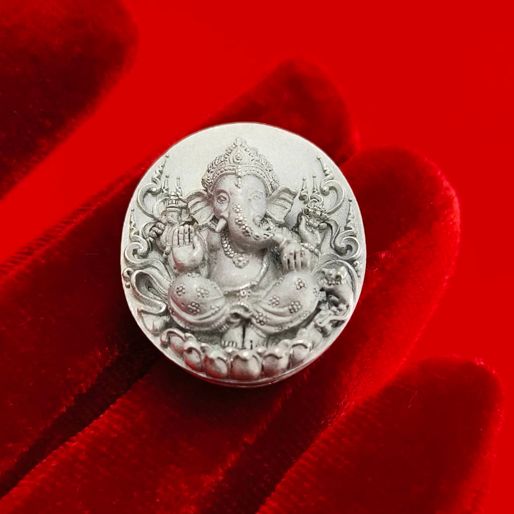 Sacred Ganesha talisman for fortune featuring intricate design on a silver coin placed on a red velvet background