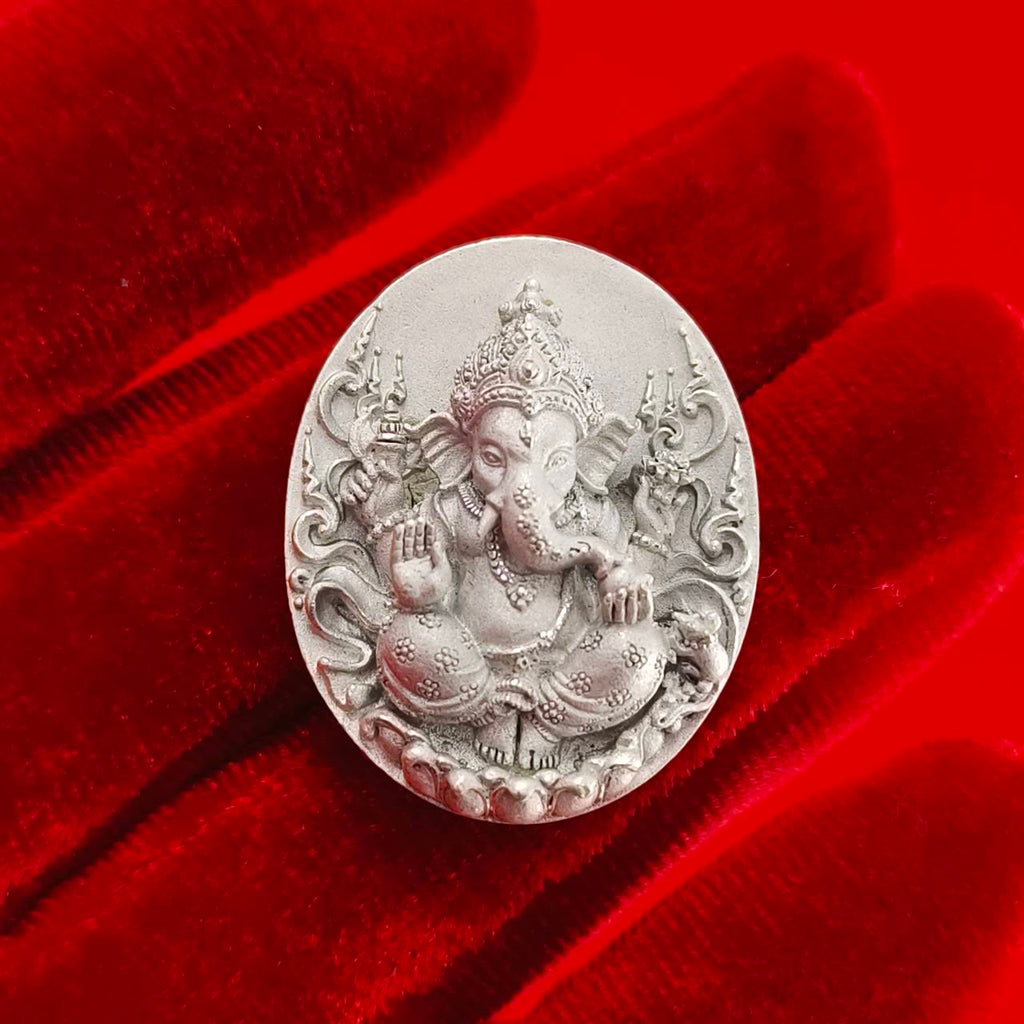 Silver Sacred Ganesha talisman for fortune on a red velvet background symbolizing prosperity and blessings