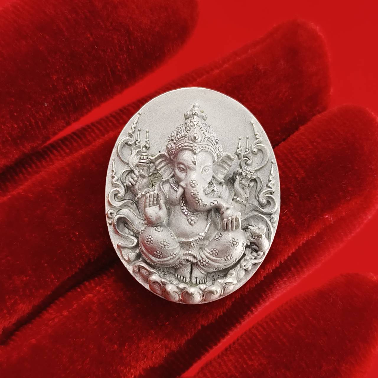 Silver Sacred Ganesha talisman for fortune on a red velvet background symbolizing prosperity and blessings