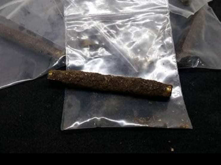 Sacred Thai amulet for good fortune displayed in a clear bag with a dark background