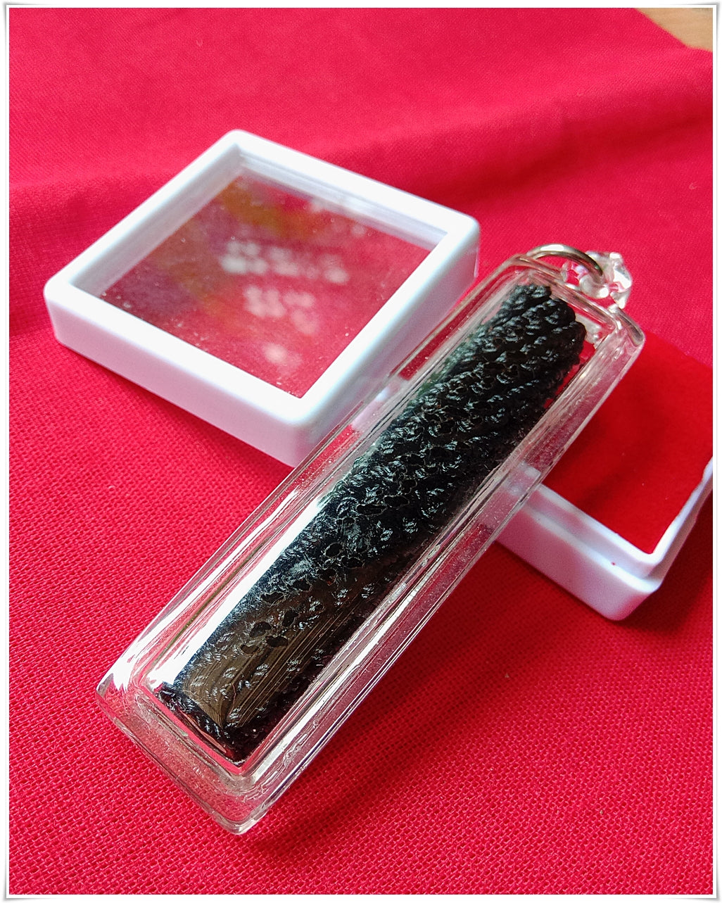 Sacred Thai amulet for good fortune in a clear case with a reflective backing