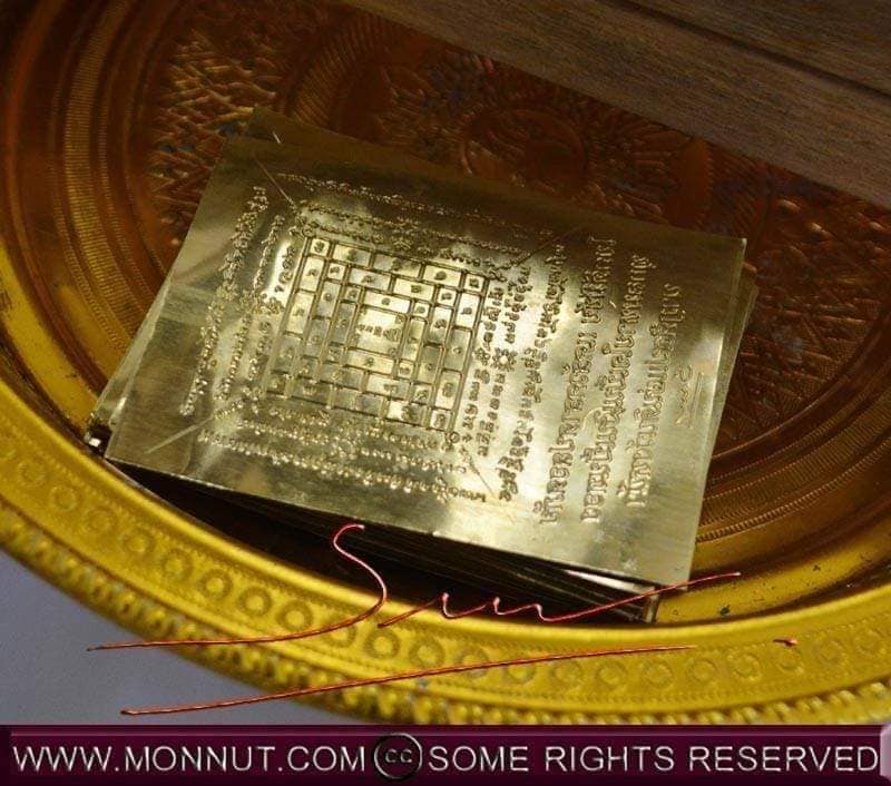 Sacred Thai amulet for good fortune resting on a decorative gold plate with intricate designs