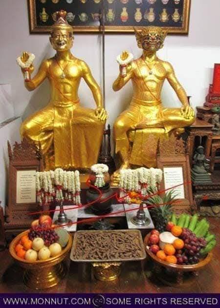 Sacred Thai amulet for good fortune displayed with golden statues and offerings of fruits and flowers