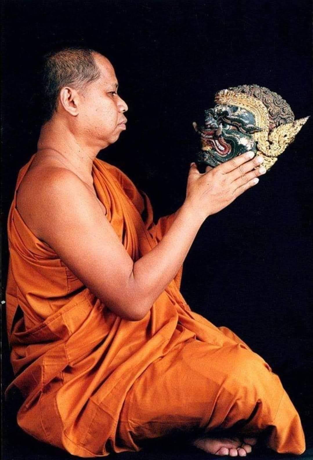 Buddhist monk holding a traditional mask, representing sacred thai amulet for good fortune