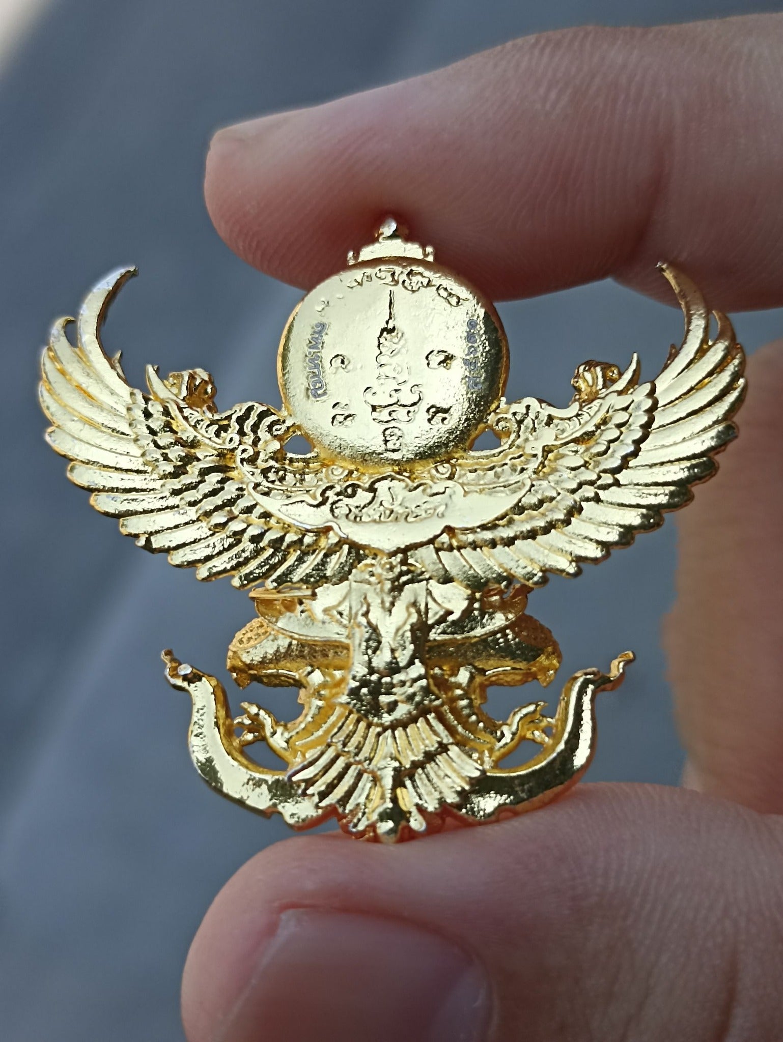 Sacred Thai elephant-bird amulet in gold with intricate detailing, held by a hand for spiritual protection