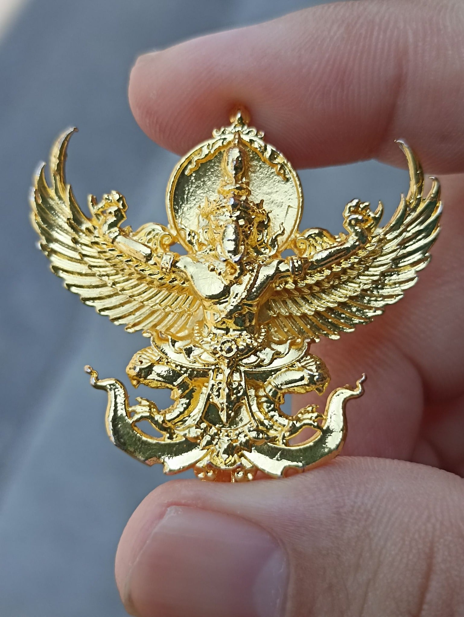 Golden Sacred Thai elephant-bird amulet held in hand, symbolizing protection and spirituality