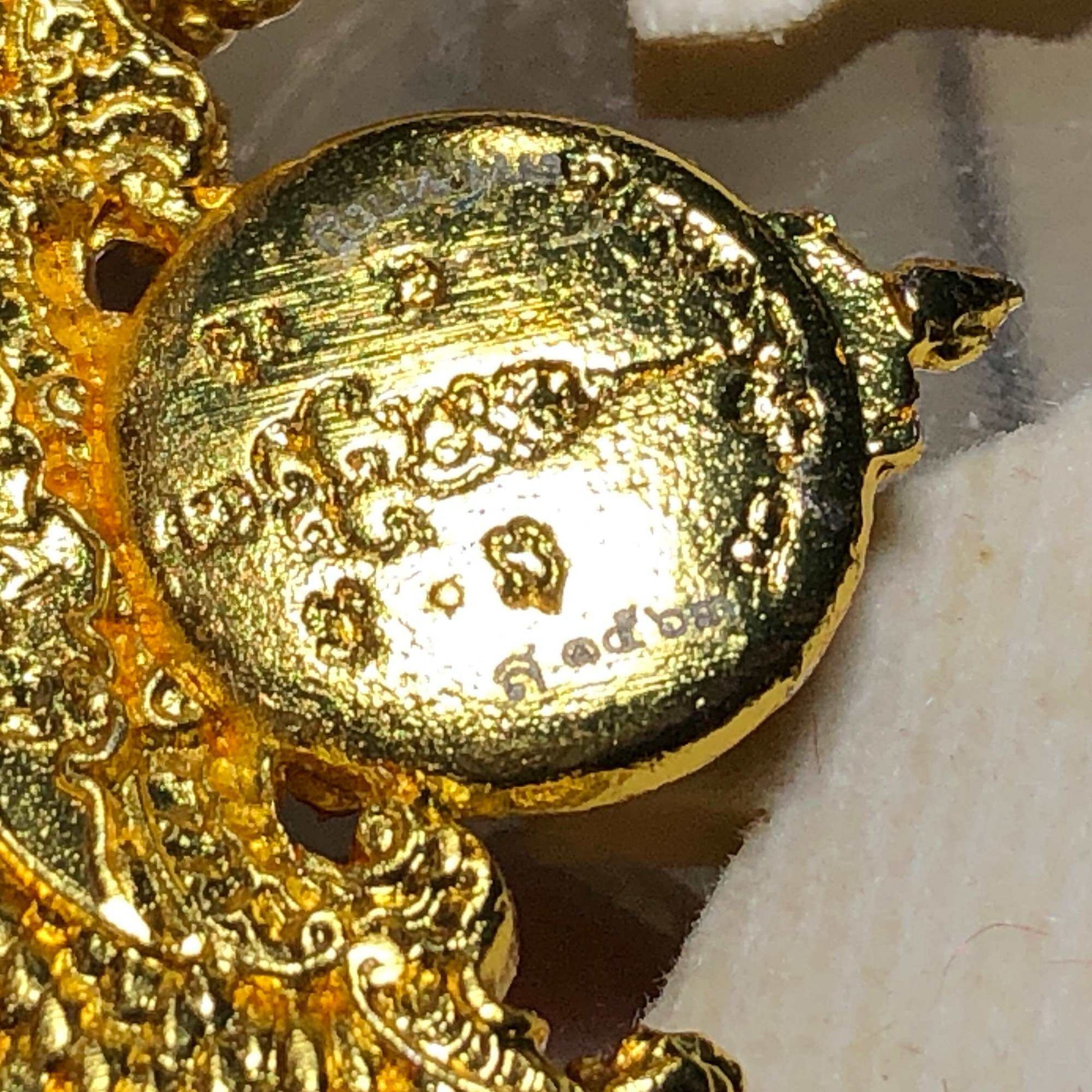 Close-up of a Sacred Thai elephant-bird amulet with intricate gold detailing and religious inscriptions