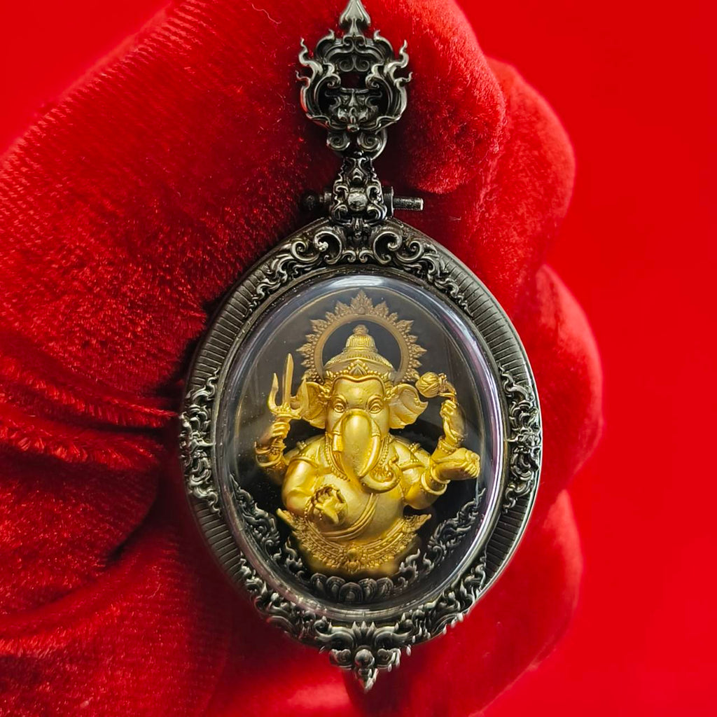 Thai Ganesh pendant white satin gold ornate oval amulet with gold Ganesh in decorative silver frame held against red background