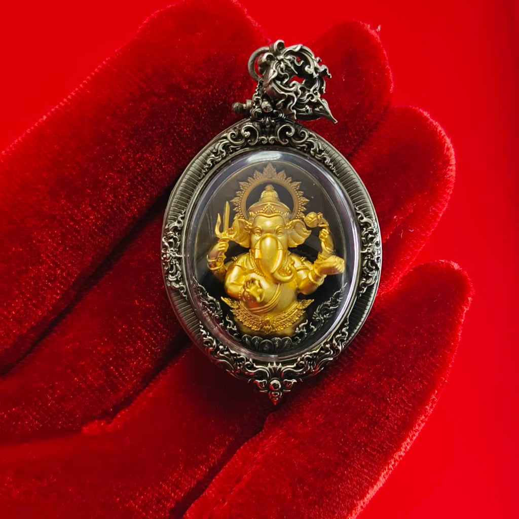 Thai Ganesh pendant white satin gold ornate oval amulet in silver filigree frame resting on red velvet glove