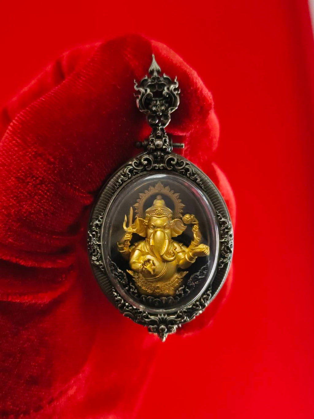 Thai Ganesh pendant white satin gold ornate oval amulet with gold Ganesha in antique silver frame on red glove background