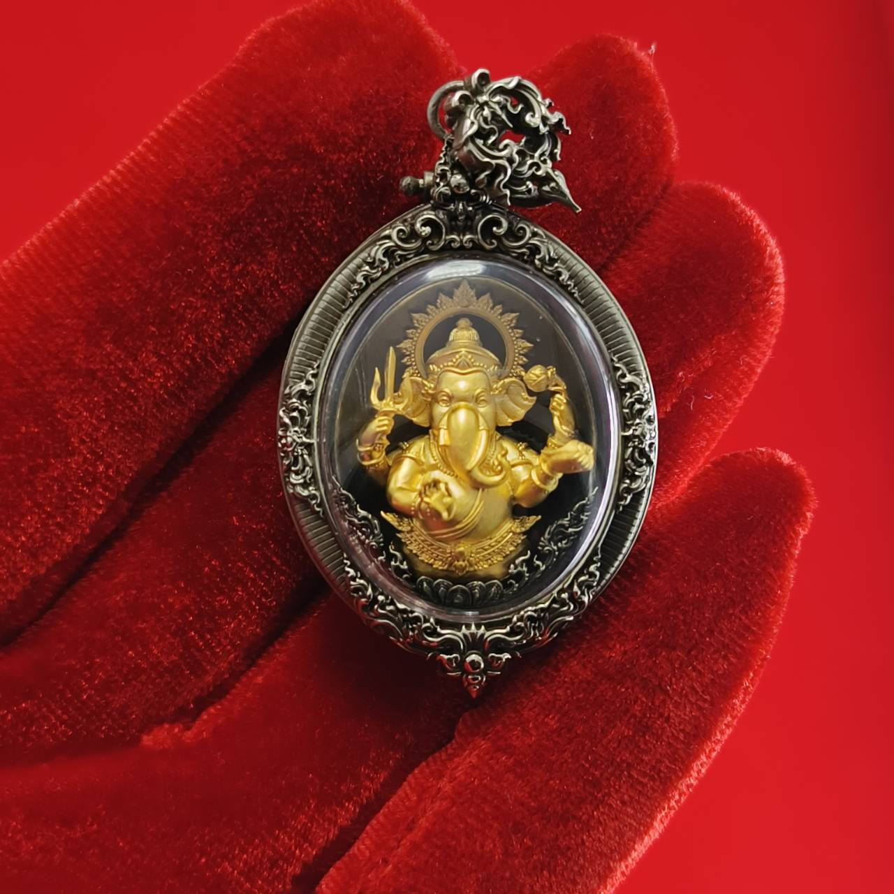 Thai Ganesh pendant white satin gold on ornate silver amulet frame resting on red velvet glove