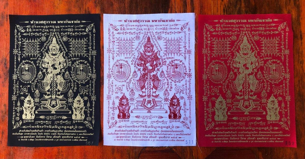 Three Phaya Wes Suwan yantra cloth amulets in black white and red showing deity and sacred script