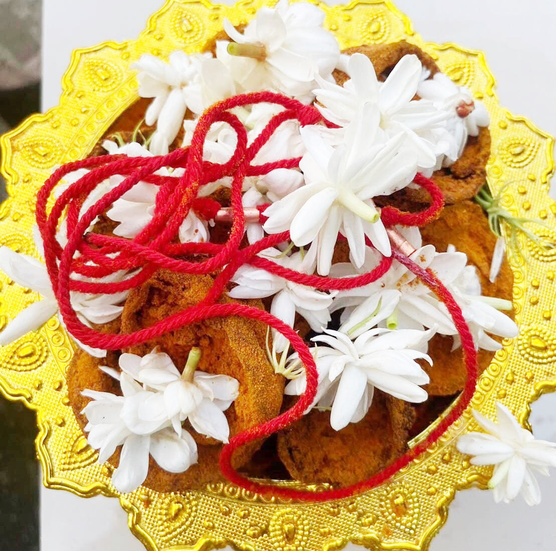 Thai wild cat placenta amulet on gold tray with red cord and white jasmine flowers ceremonial display