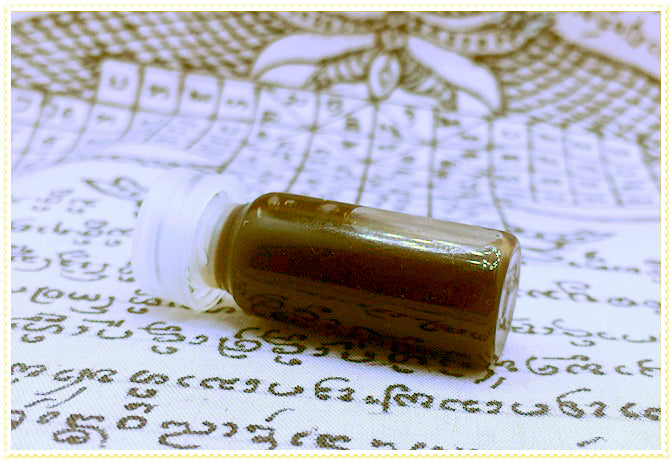 Thai Blessing Co small vial of brown passion oil for couples on patterned script cloth