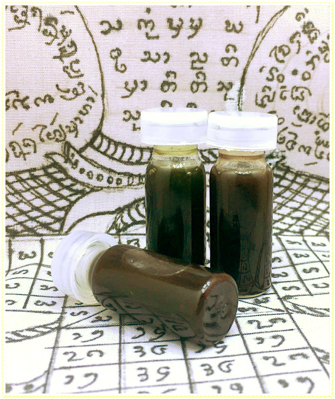 Thai Blessing Co passion oil for couples in three small glass vials with white caps on yantra cloth backdrop