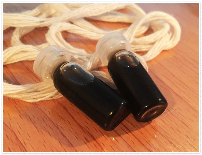 Thai Blessing Co small black glass vials with stopper and cord on wood aromatherapy passion oil for couples